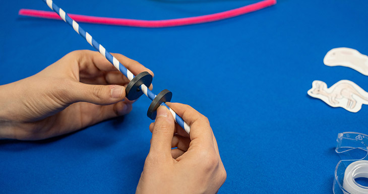 Thread two donut shaped magnets onto the straw